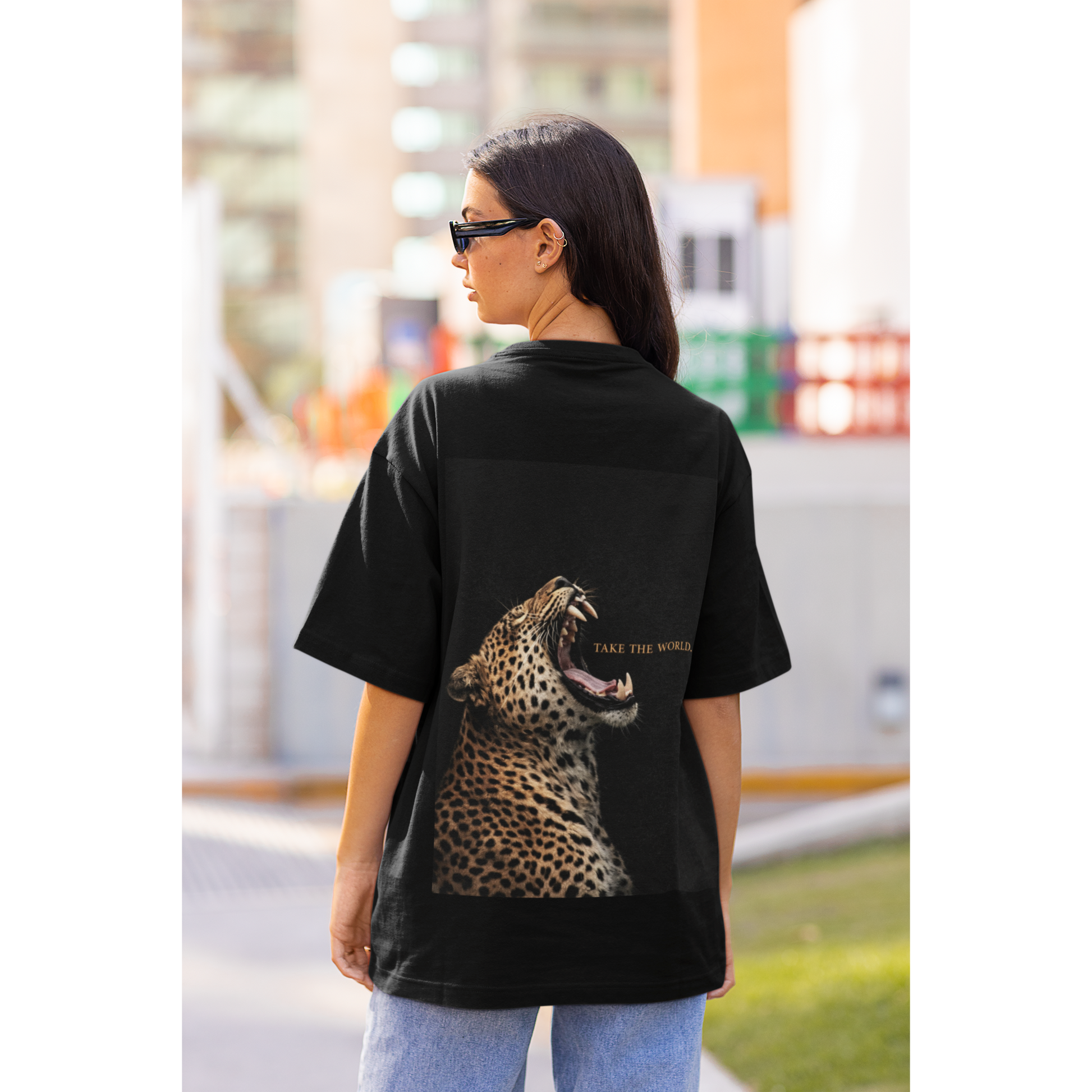 Black leopard back graphic t-shirt worn by model outdoors, roaring leopard artwork with TAKE THE WORLD text, luxury streetwear statement tee