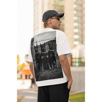 White unisex streetwear t-shirt worn by male model outdoors, back graphic featuring Doberman trio artwork, motivational fashion focused on discipline, dominance, and mental resilience