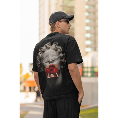 Black t-shirt worn outdoors by male model, blindfolded classical statue back artwork with red lollipops, dark luxury street style tee