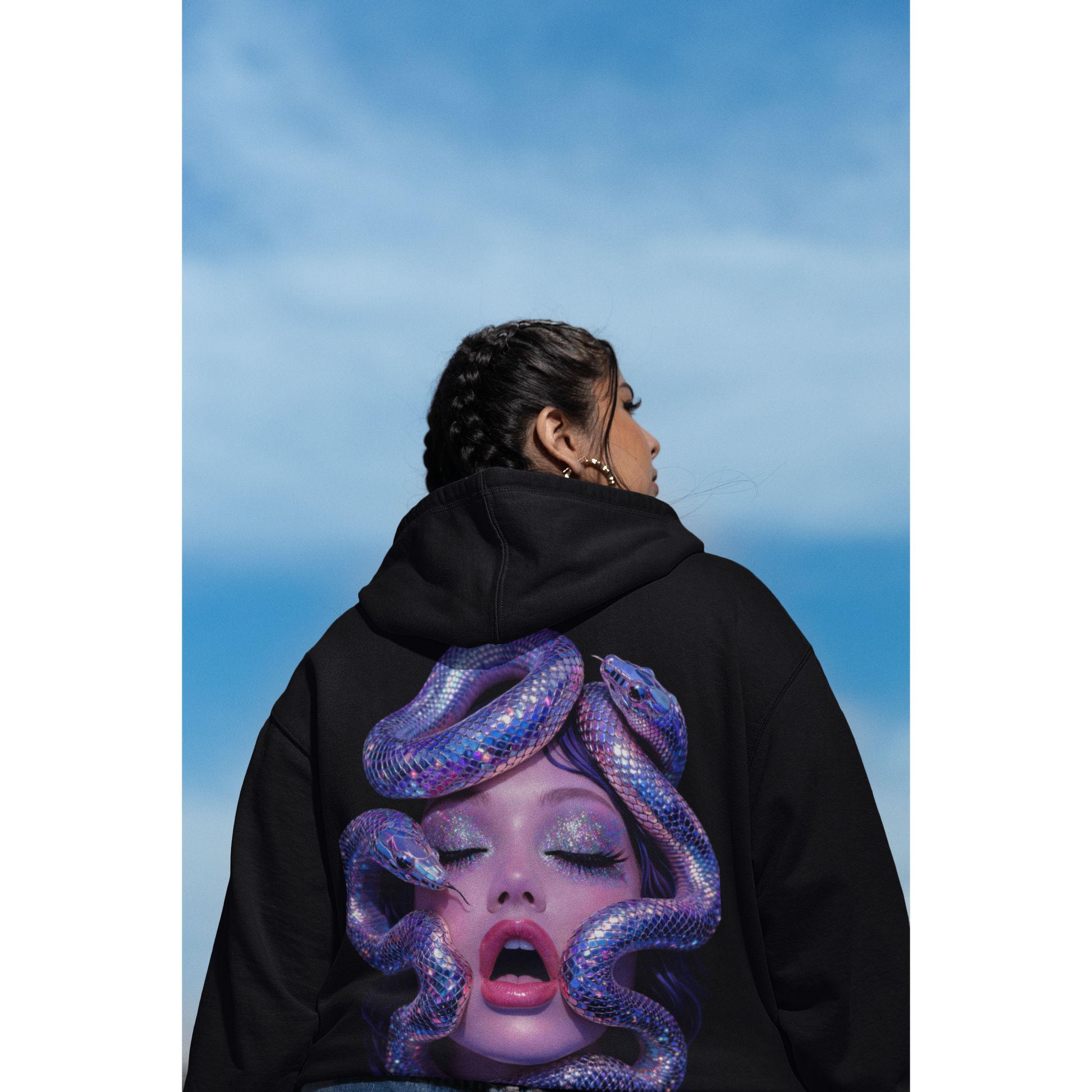 Black statement hoodie worn outdoors featuring surreal serpent glamour back artwork, modern streetwear with iridescent snake portrait