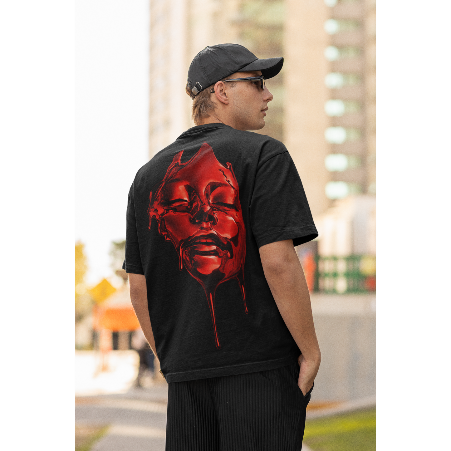 Male model wearing black red liquid face back graphic t-shirt, dark luxury streetwear tee featuring high-gloss red fluid face artwork with dripping details on unisex black t-shirt in outdoor urban setting
