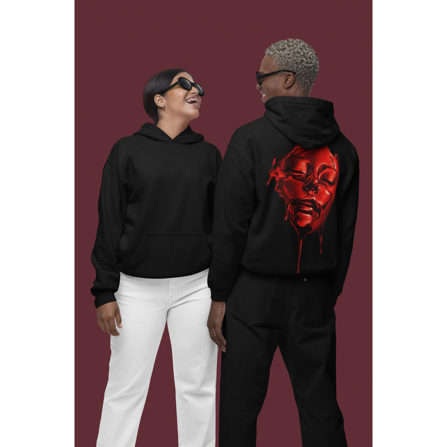 Two models wearing black hoodies, one shown from the back displaying red liquid face back graphic, unisex dark luxury streetwear hoodie with clean front and bold surreal artwork