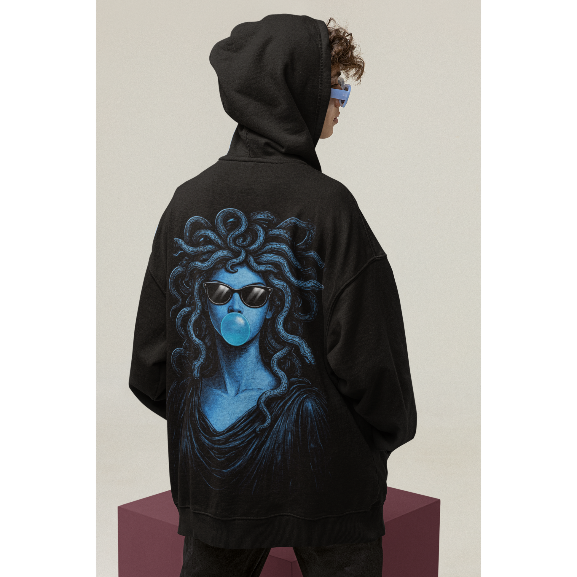 Male model wearing black blue medusa bubblegum back graphic hoodie with hood up, dark luxury statement hoodie featuring blue Medusa artwork with sunglasses and bubblegum, unisex pullover hoodie with clean front and bold back graphic