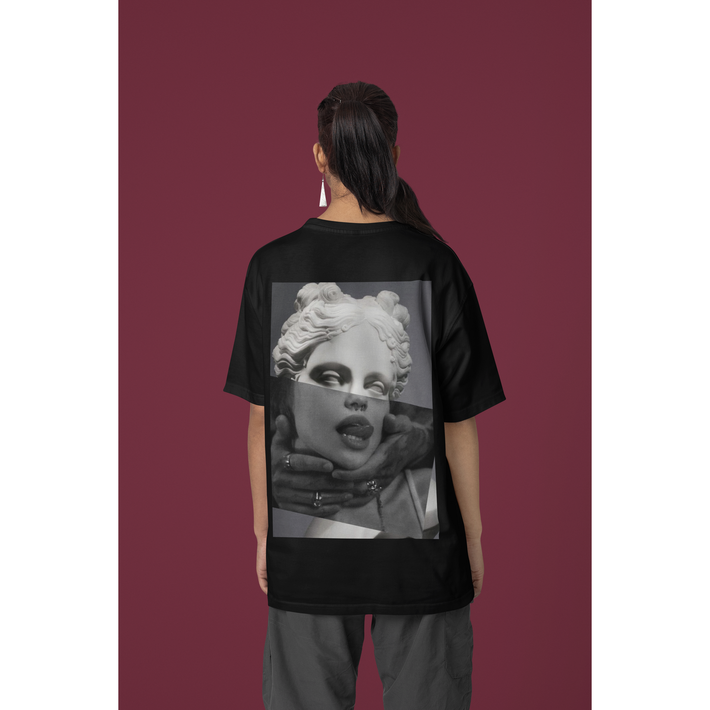Female model wearing plain black surreal statue statement t-shirt in studio setting, unisex dark luxury streetwear tee featuring clean minimalist front design and bold surreal back artwork