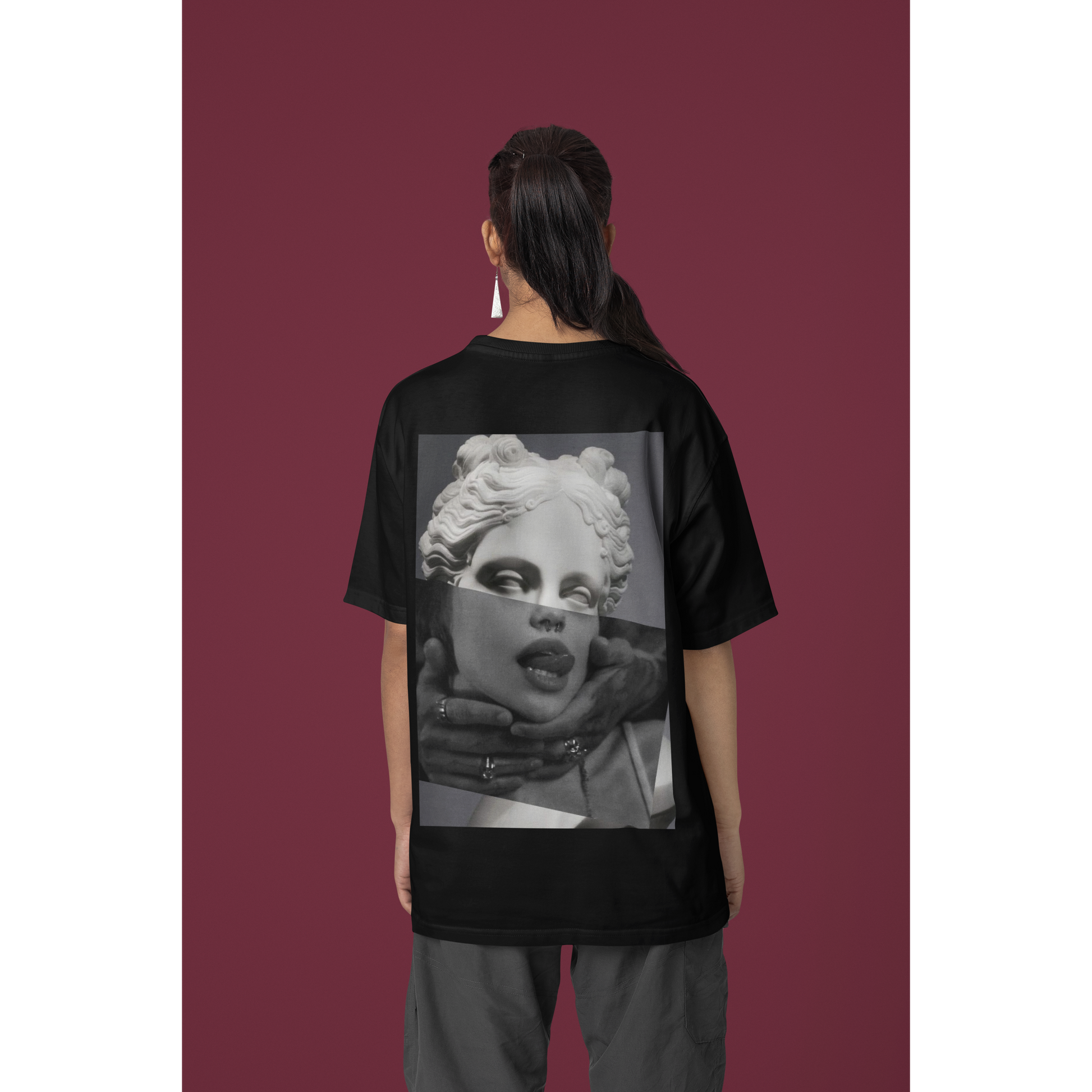Female model wearing plain black surreal statue statement t-shirt in studio setting, unisex dark luxury streetwear tee featuring clean minimalist front design and bold surreal back artwork