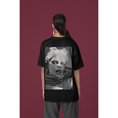 Female model wearing plain black surreal statue statement t-shirt in studio setting, unisex dark luxury streetwear tee featuring clean minimalist front design and bold surreal back artwork