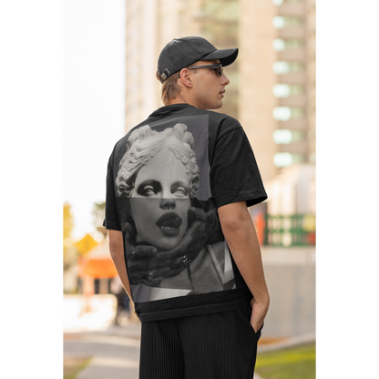 Male model wearing black surreal statue back graphic t-shirt outdoors, dark luxury streetwear tee featuring bold classical statue collage artwork on the back with clean minimalist front design