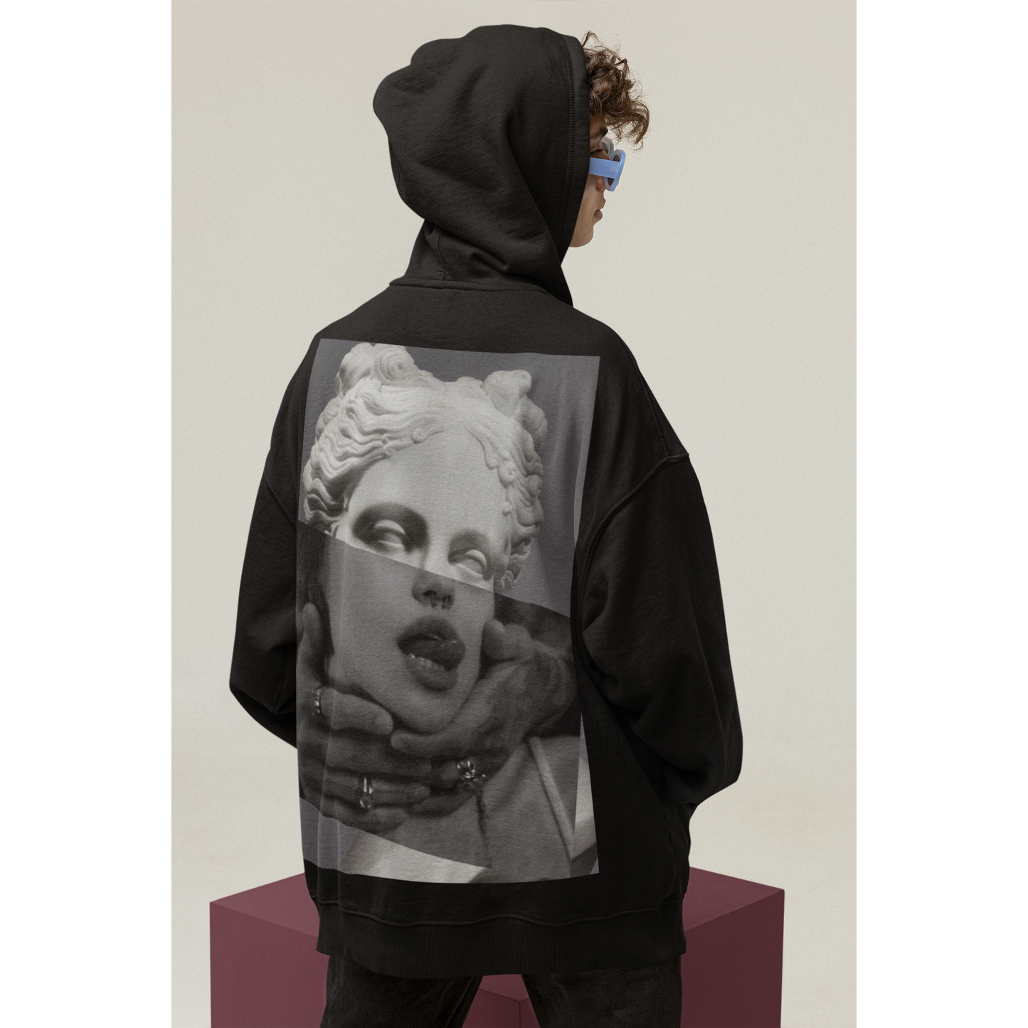 Black surreal statue back graphic hoodie shown in studio with hood up, unisex premium streetwear hoodie featuring surreal classical statue collage artwork printed on the back and clean front silhouette