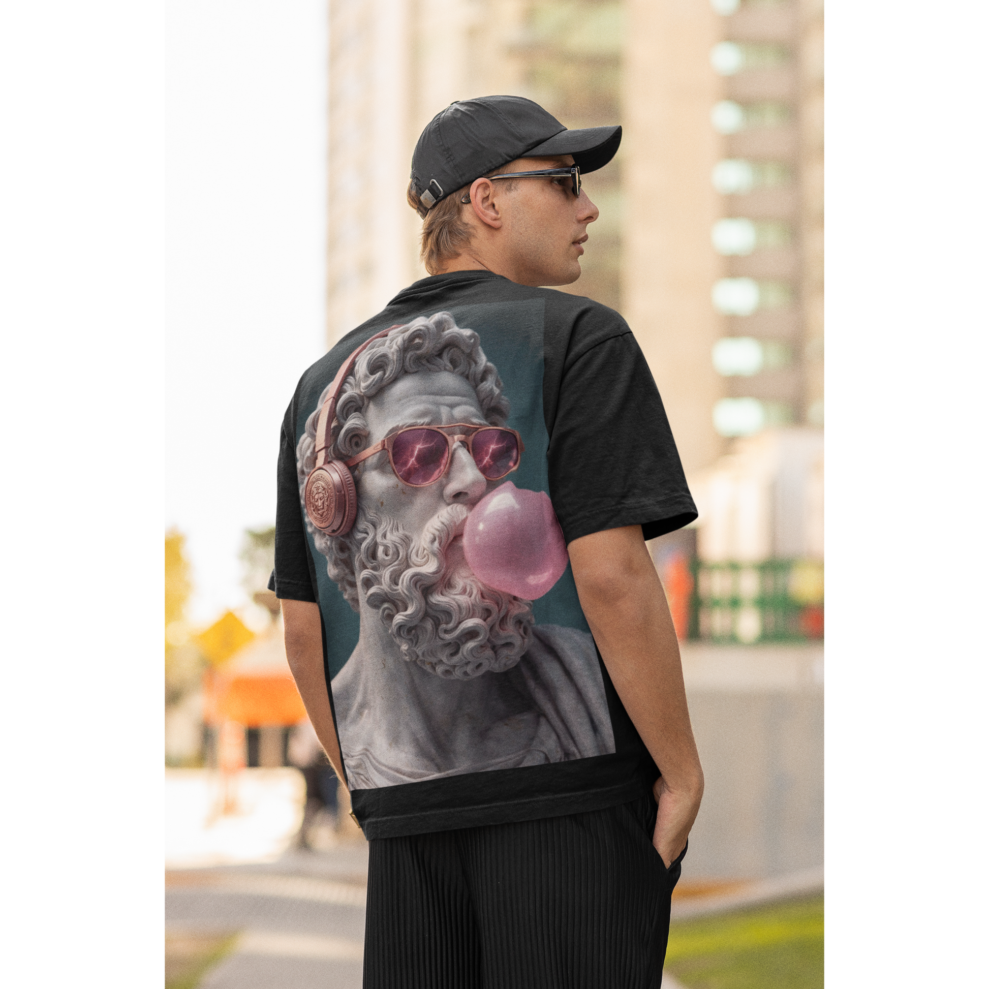 Lifestyle shot of male model wearing black classical statue headphones bubblegum back graphic t-shirt outdoors, dark luxury streetwear tee featuring marble statue with headphones and pink bubblegum and clean black front