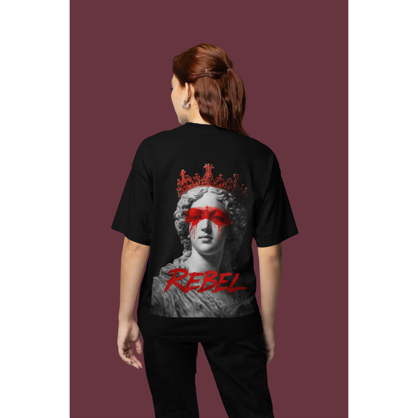 Model wearing black Rebel classical statue back graphic t-shirt, unisex dark luxury streetwear tee featuring crowned marble sculpture with red paint across the eyes and “REBEL” text, clean black front design