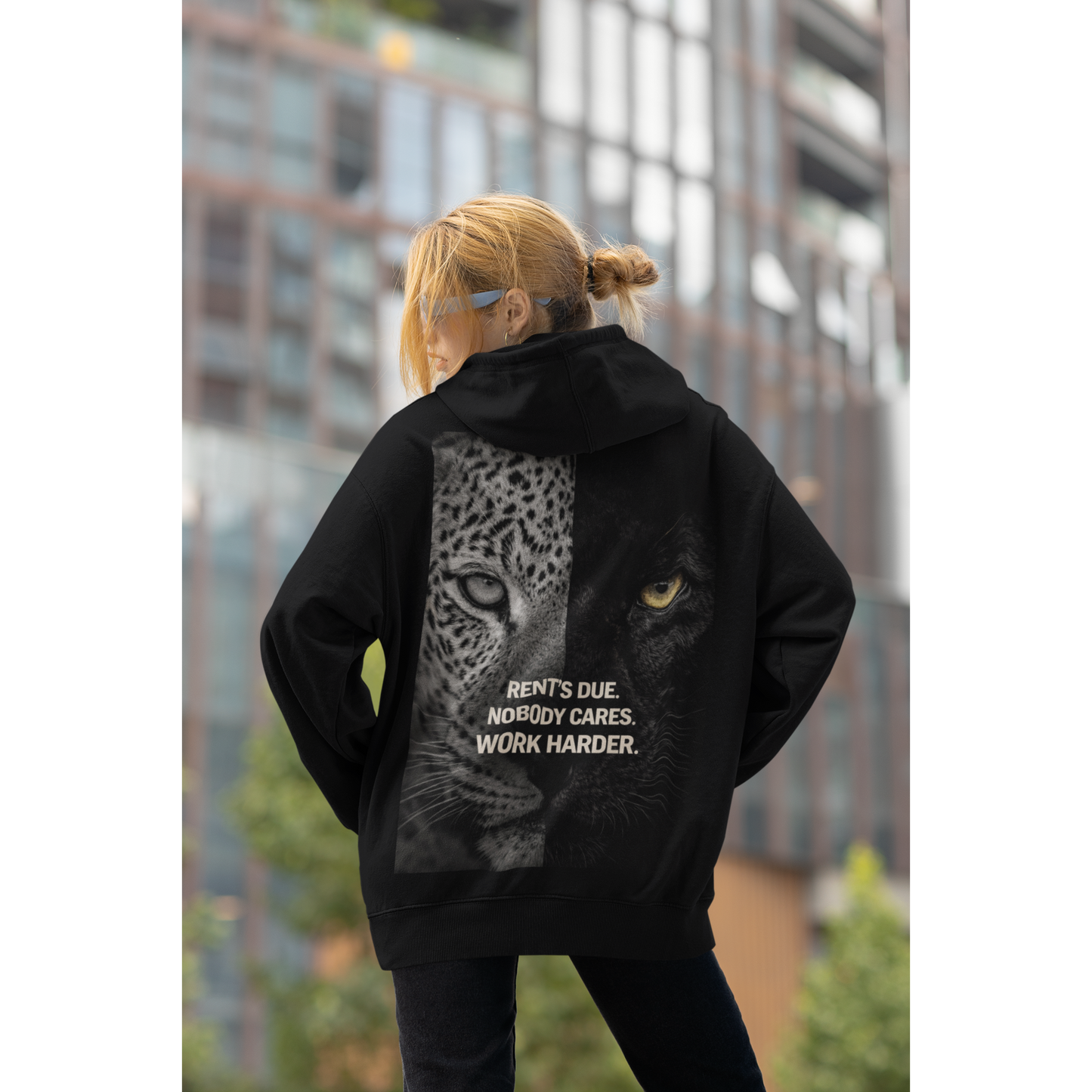 Model wearing black unisex hoodie with leopard panther back graphic and motivational quote dark luxury streetwear worn in urban city environment