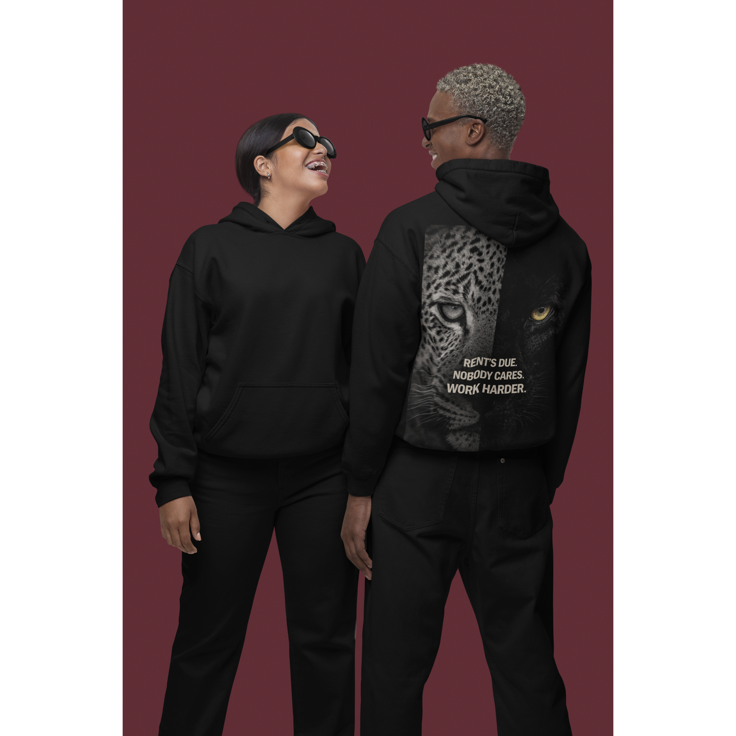 Two models wearing black unisex pullover hoodies featuring clean front and leopard panther back graphic with “Rent’s Due. Nobody Cares. Work Harder.” statement