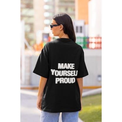 Person wearing a black t-shirt with 'MAKE YOURSELF PROUD' text on the back, standing outdoors. Unisex black statement t-shirt worn in modern streetwear style
