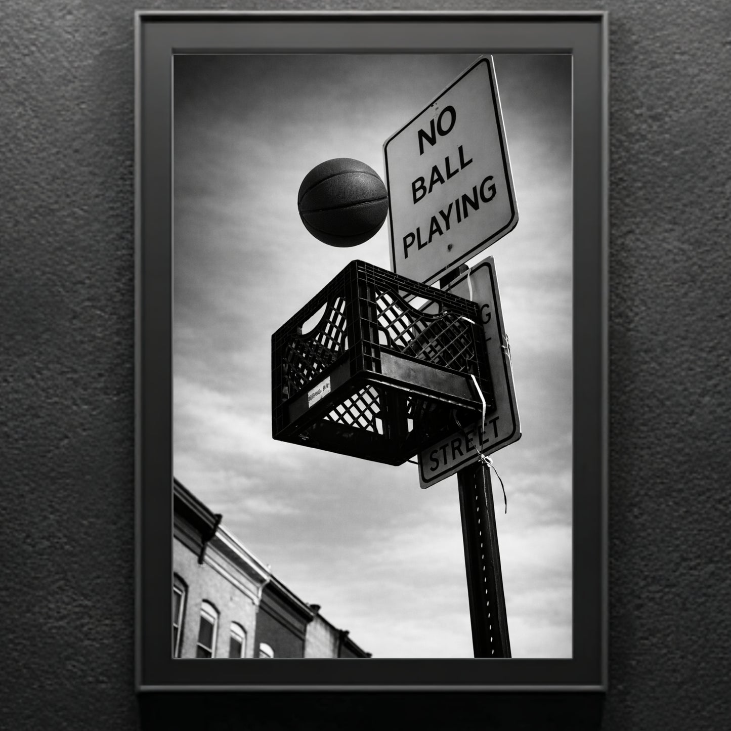Close up black and white street basketball wall art in black frame, milk crate hoop mounted under no ball playing street sign urban photography print