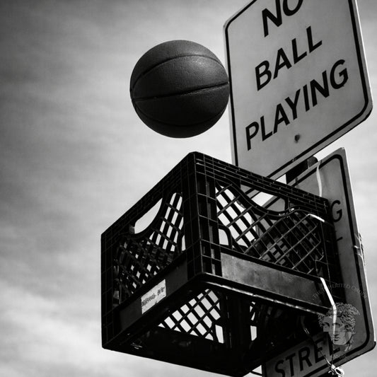 Close up black and white milk crate basketball hoop under no ball playing street sign, gritty urban sports photography artwork