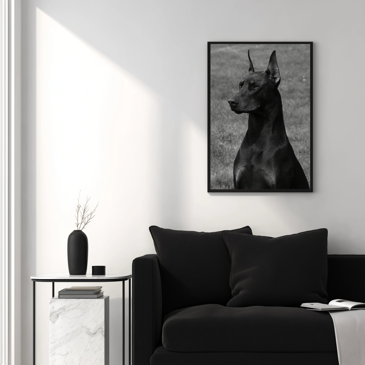 Black and white Doberman portrait wall art displayed above modern black sofa in minimalist interior