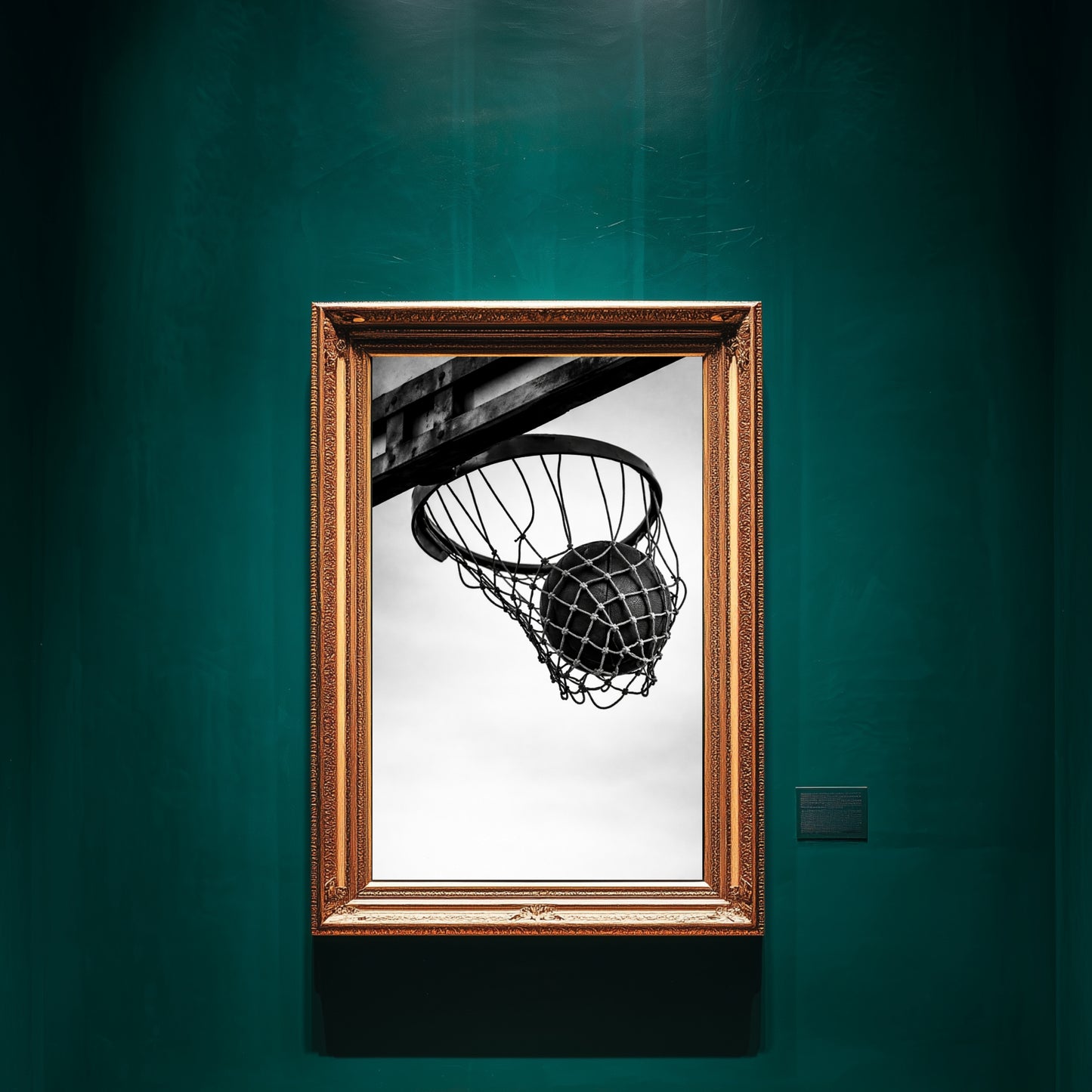Black and white basketball hoop wall art in ornate gold frame displayed on deep green gallery wall, minimalist sports photography print featuring ball suspended in net