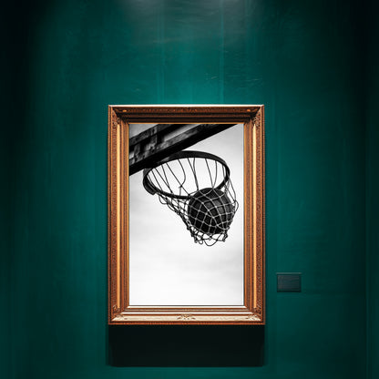 Black and white basketball hoop wall art in ornate gold frame displayed on deep green gallery wall, minimalist sports photography print featuring ball suspended in net