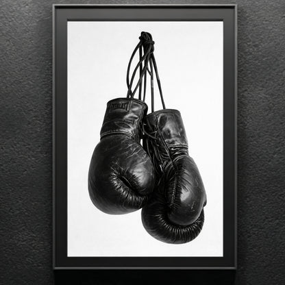 Black and white boxing gloves wall art in modern black frame against textured gray wall, vertical monochrome sports photography print for gym or office decor