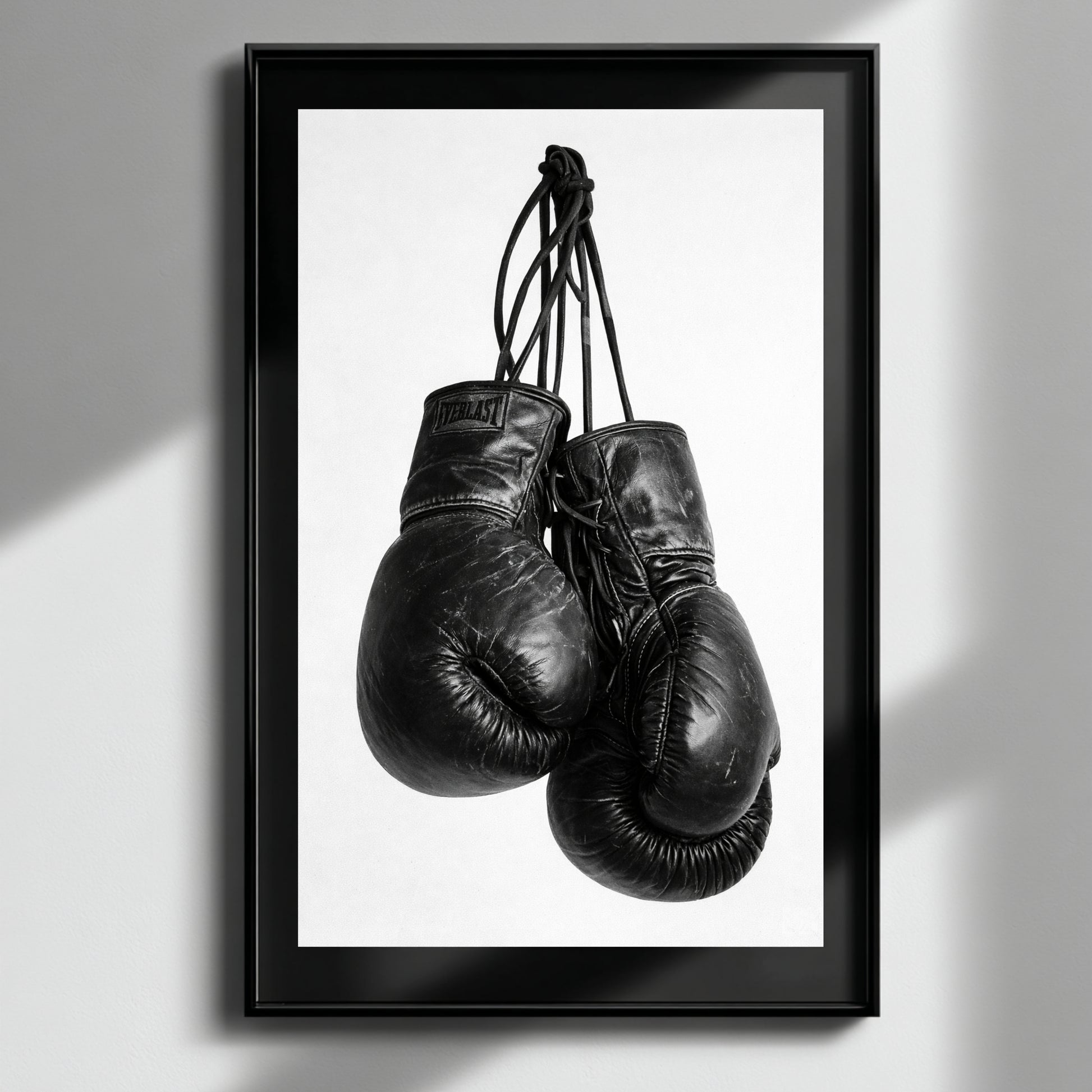 Framed black and white boxing gloves wall art on neutral wall, vertical monochrome sports photography print for gym office or studio decor