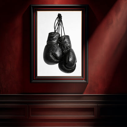Monochrome boxing gloves wall art in black frame on dark red wall, high contrast sports photography print for gym wall decor and modern masculine interior design