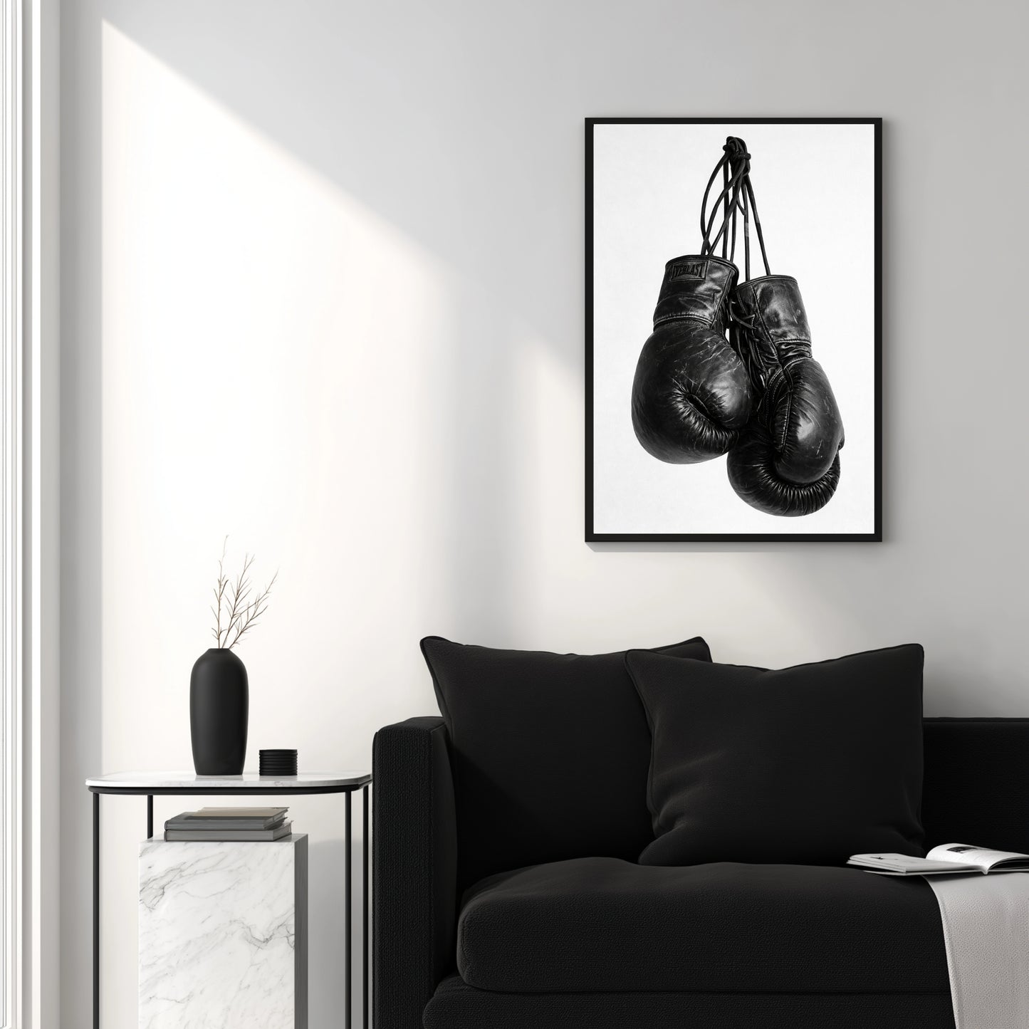 Black and white boxing gloves wall art above modern black sofa, minimalist sports photography print for clean contemporary interior design