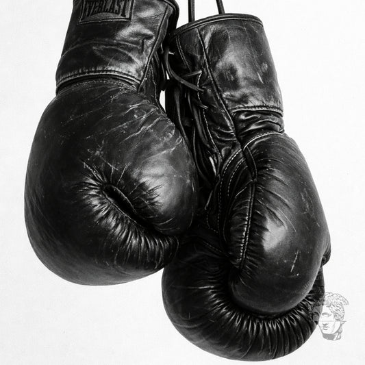Close-up black and white boxing gloves photography print showing worn leather texture and laces, high contrast minimalist sports wall art detail