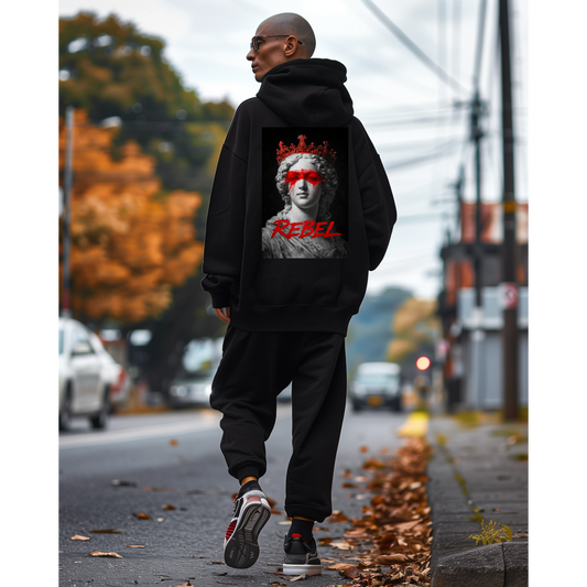 Black unisex pullover hoodie worn outdoors, back view featuring rebel classical statue graphic with red crown and paint detail, dark luxury streetwear hoodie styled in urban setting