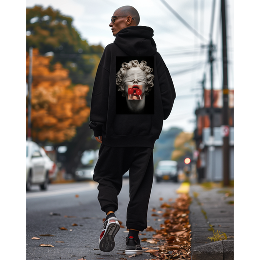 Black hoodie worn outdoors by model, back graphic featuring blindfolded classical statue with red lollipops, dark luxury street style